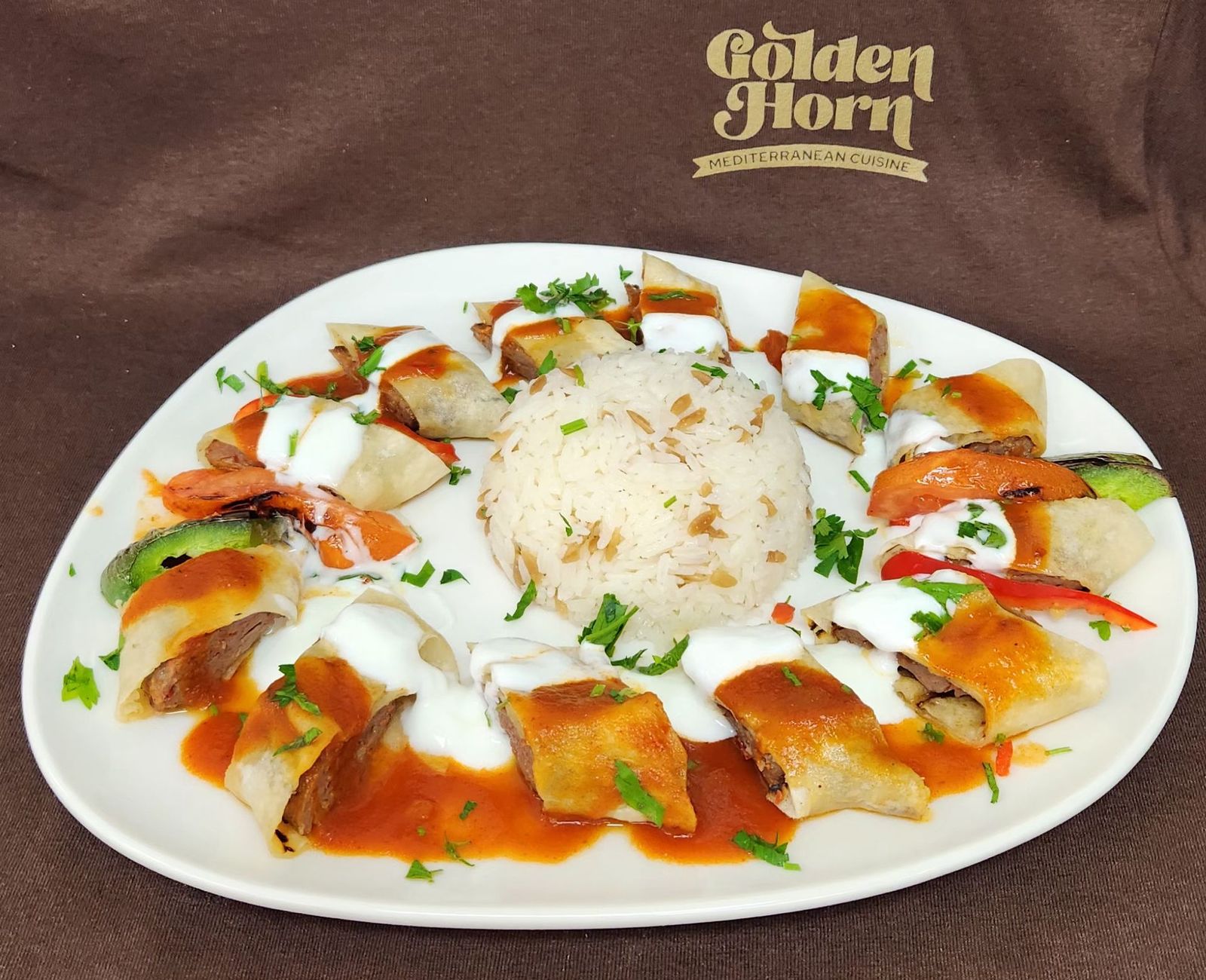 Beyti kebab with tomato and yogurt sauces around rice