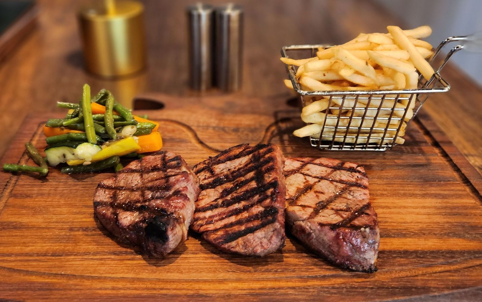 Grilled beef tenderloin on a wooden board with fries
